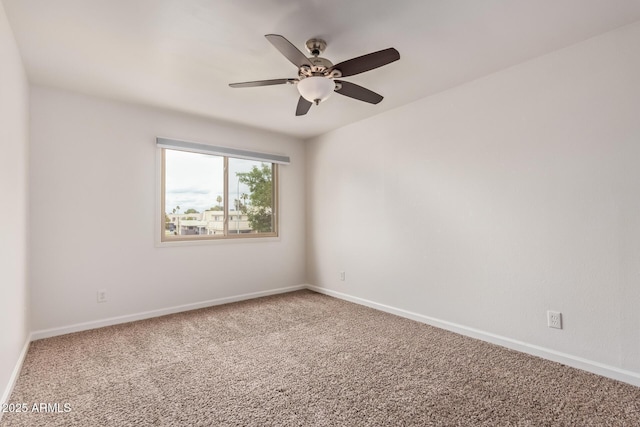 carpeted empty room with a ceiling fan and baseboards