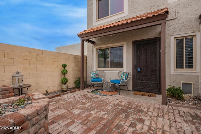 doorway to property featuring stucco siding, a patio, and fence