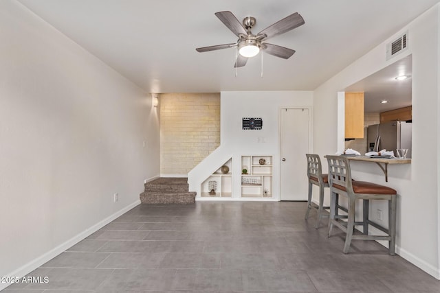 living area featuring stairway, baseboards, visible vents, and ceiling fan