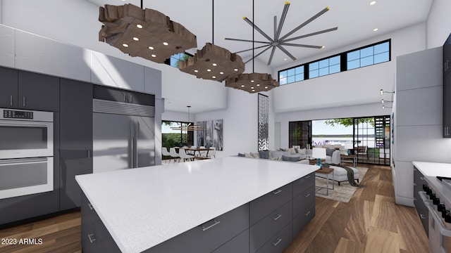 kitchen featuring decorative light fixtures, a kitchen island, dark hardwood / wood-style floors, and a high ceiling