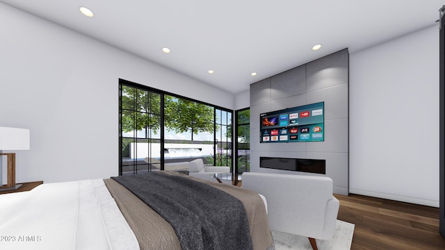 bedroom featuring dark hardwood / wood-style flooring, a water view, and a fireplace