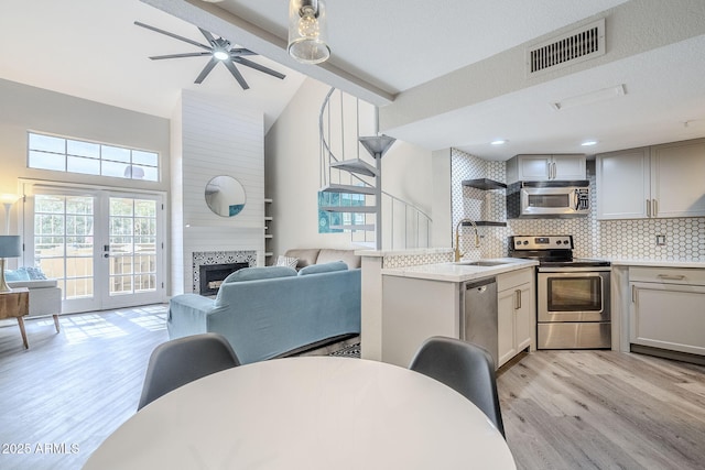 kitchen with french doors, stainless steel appliances, light hardwood / wood-style floors, and decorative backsplash