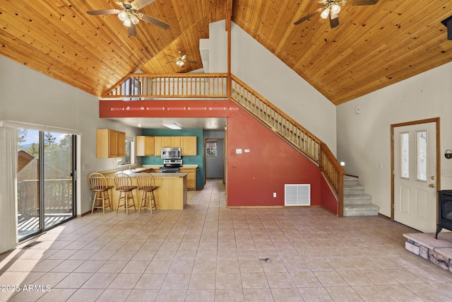 unfurnished living room with high vaulted ceiling, a wood stove, light tile patterned floors, and wood ceiling