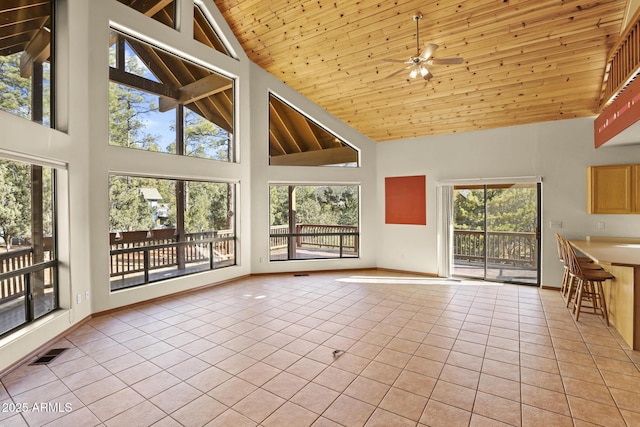 unfurnished sunroom with ceiling fan, a healthy amount of sunlight, and wooden ceiling