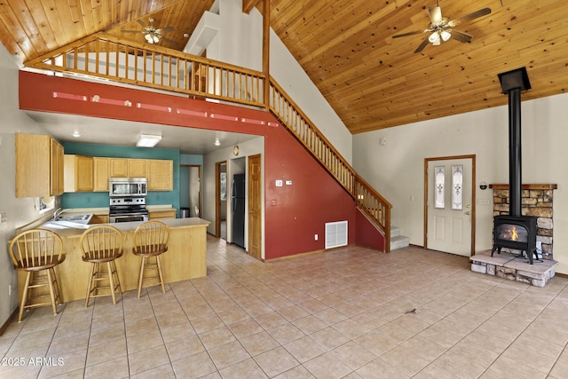 kitchen with appliances with stainless steel finishes, a kitchen bar, kitchen peninsula, high vaulted ceiling, and wooden ceiling