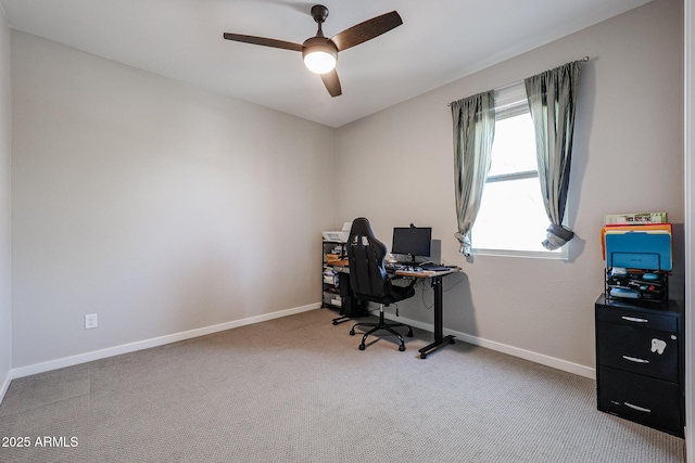 carpeted office space featuring a ceiling fan and baseboards