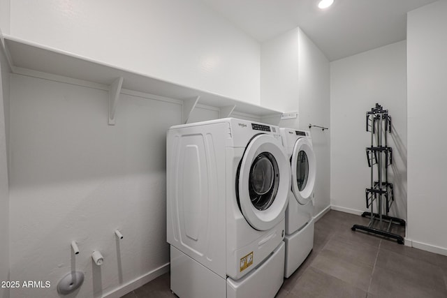 laundry area with laundry area, washing machine and dryer, baseboards, and dark tile patterned flooring