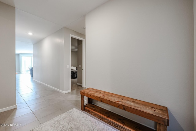 hall featuring baseboards and light tile patterned floors