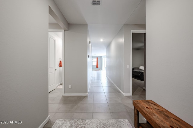 corridor with visible vents, baseboards, and light tile patterned flooring