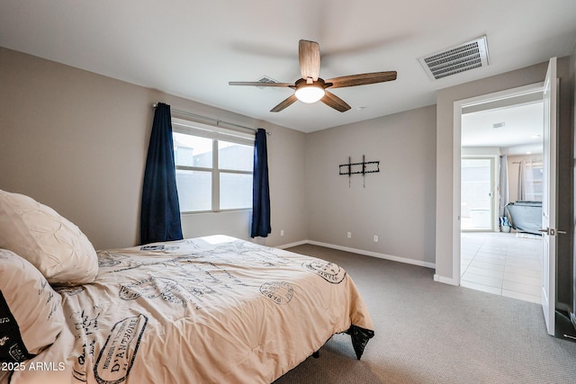 carpeted bedroom featuring a ceiling fan, tile patterned flooring, visible vents, and baseboards