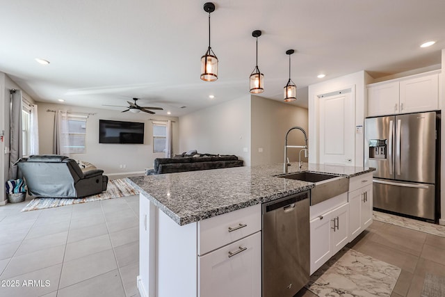 kitchen with stainless steel appliances, an island with sink, a sink, and white cabinetry