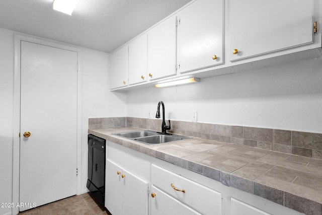 kitchen featuring dishwasher, sink, light tile patterned floors, and white cabinets