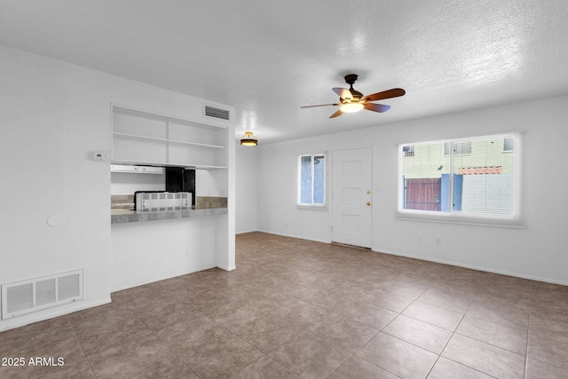 unfurnished living room featuring ceiling fan and a textured ceiling