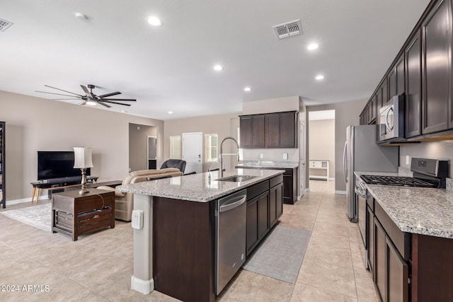 kitchen featuring stainless steel appliances, a center island with sink, dark brown cabinetry, and sink