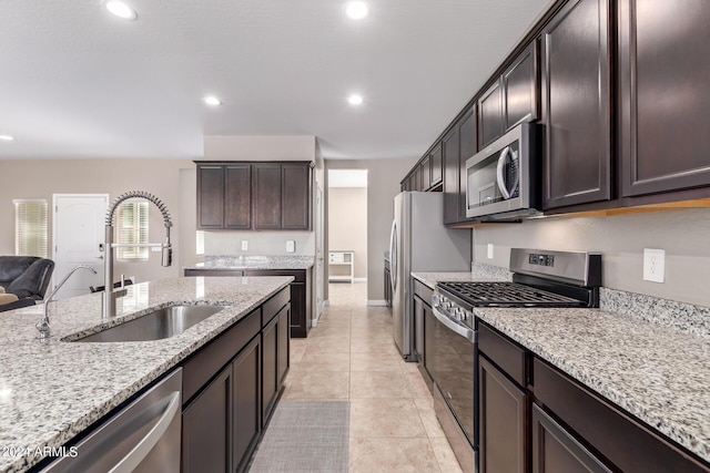 kitchen featuring light stone countertops, sink, appliances with stainless steel finishes, and light tile patterned floors