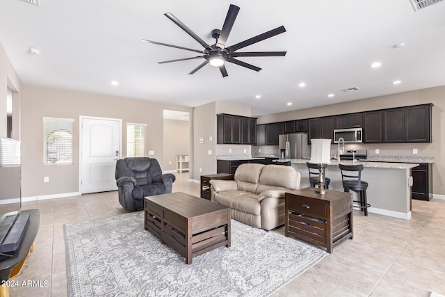 tiled living room with ceiling fan and sink