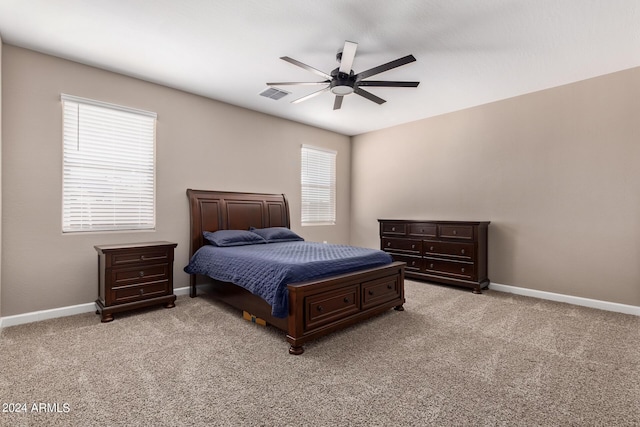 bedroom with ceiling fan, light colored carpet, and multiple windows