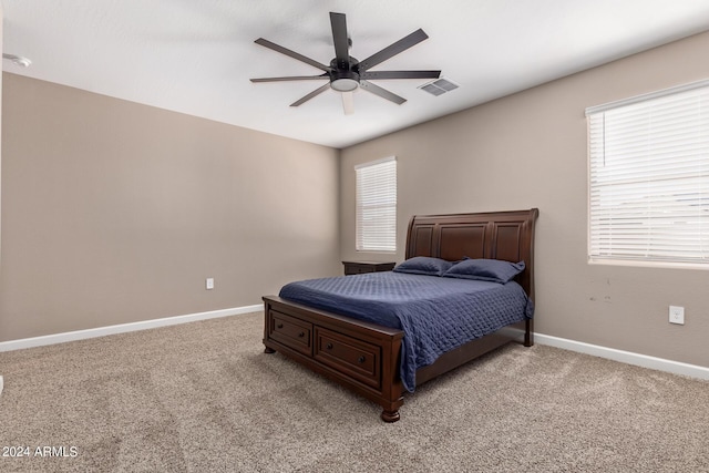 bedroom featuring ceiling fan, light carpet, and multiple windows