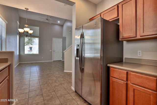 14870 W Encanto Blvd Unit 1038, Goodyear, AZ 85395 - kitchen with stainless steel fridge, a chandelier, brown cabinetry, pendant lighting, and light tile patterned flooring