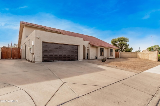 mediterranean / spanish-style home with an attached garage, a tile roof, and stucco siding