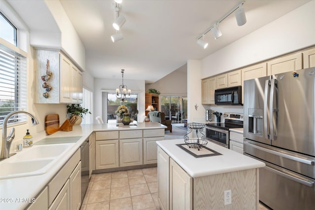 kitchen featuring appliances with stainless steel finishes, light countertops, a sink, and hanging light fixtures