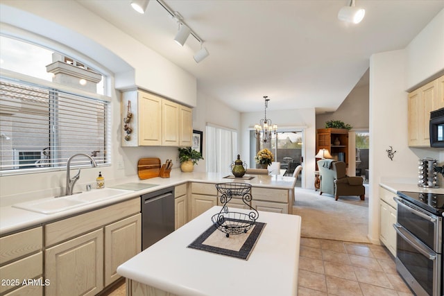 kitchen featuring appliances with stainless steel finishes, light countertops, a sink, and decorative light fixtures