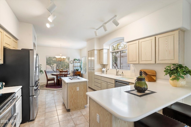 kitchen featuring a kitchen island, appliances with stainless steel finishes, light countertops, pendant lighting, and a sink