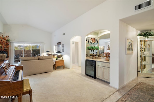 living room with a dry bar, light carpet, visible vents, arched walkways, and wine cooler