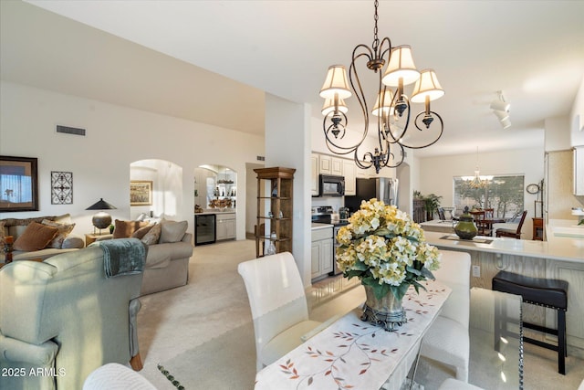 dining area with beverage cooler, visible vents, arched walkways, light colored carpet, and a notable chandelier