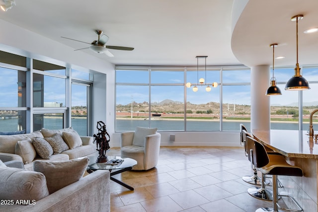 living room with ceiling fan and a water view