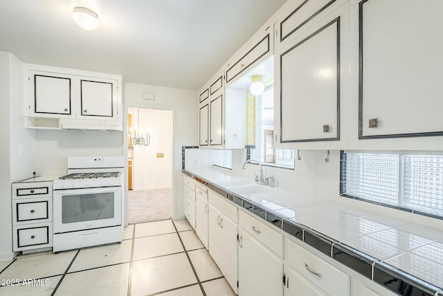 1945 E Solano Dr, Phoenix, AZ 85016 - kitchen featuring white gas range oven, tile countertops, white cabinets, backsplash, and under cabinet range hood