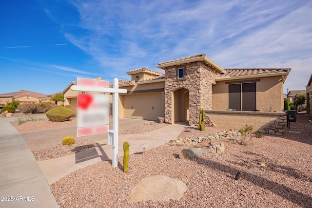 mediterranean / spanish-style house with stucco siding, concrete driveway, an attached garage, stone siding, and a tiled roof