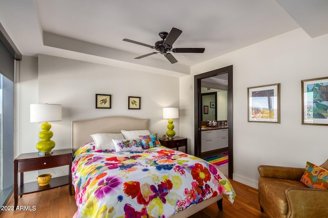 bedroom with ceiling fan, connected bathroom, and hardwood / wood-style flooring