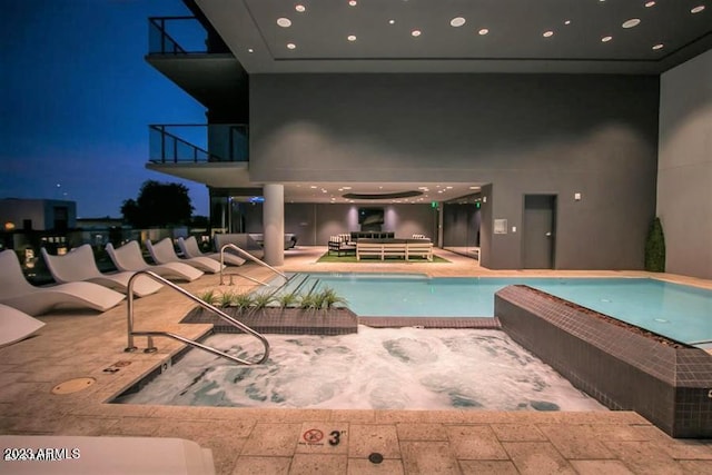 pool at night with a patio area and outdoor lounge area