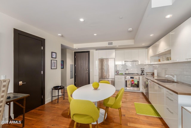 kitchen featuring sink, stainless steel appliances, white cabinets, and tasteful backsplash