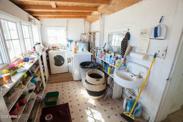 washroom featuring water heater, washer and dryer, and sink