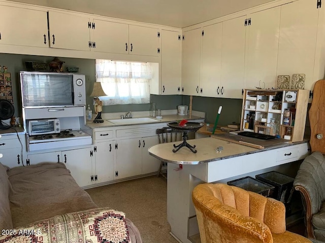 kitchen with sink, kitchen peninsula, a breakfast bar, and white cabinetry