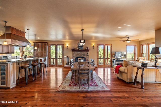 living room with french doors, ceiling fan, a stone fireplace, and dark hardwood / wood-style floors