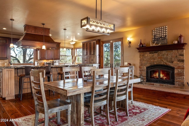 dining space with a stone fireplace and dark hardwood / wood-style floors