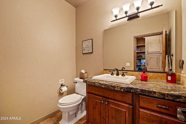 bathroom with toilet, tasteful backsplash, vanity, and tile patterned floors