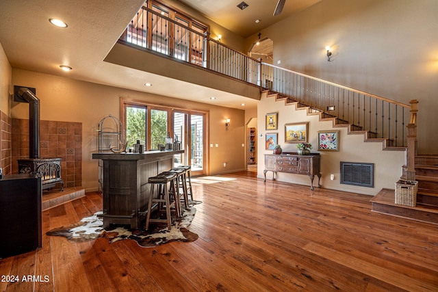 bar with a towering ceiling, a wood stove, and wood-type flooring