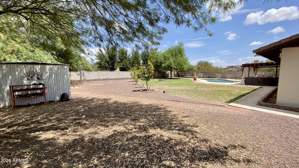 view of yard with a fenced in pool and a storage shed