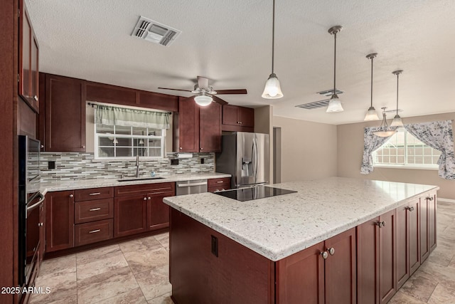 kitchen featuring visible vents, a sink, a kitchen island, tasteful backsplash, and appliances with stainless steel finishes