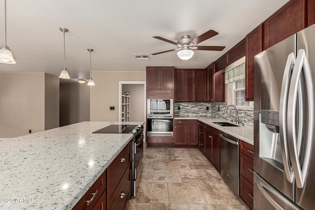 kitchen featuring visible vents, a sink, tasteful backsplash, stainless steel appliances, and light stone countertops