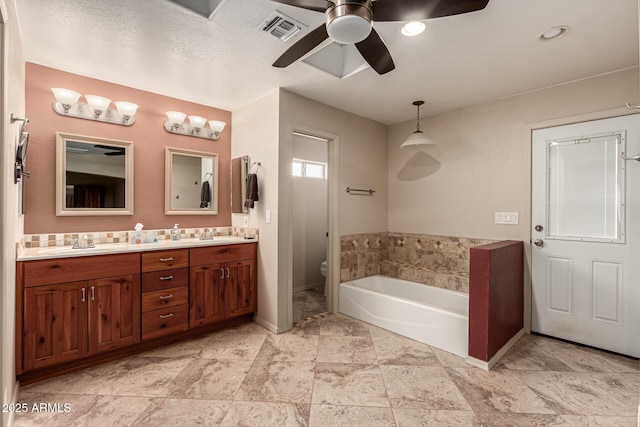 bathroom with visible vents, toilet, a garden tub, double vanity, and ceiling fan