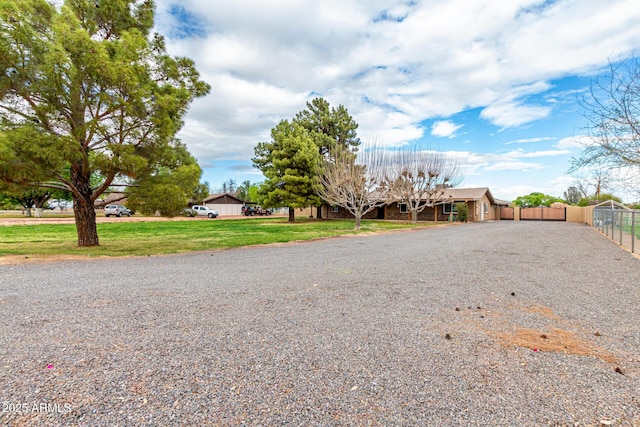 view of front facade with gravel driveway, a front yard, and fence