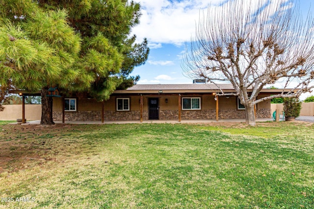 ranch-style house featuring stone siding, fence, a front lawn, and a patio area