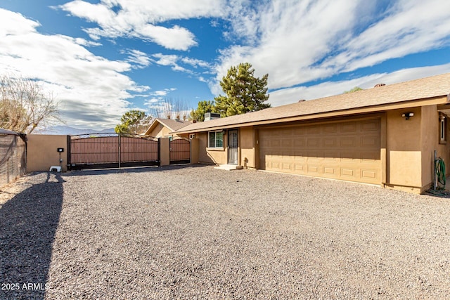 single story home featuring stucco siding, fence, an attached garage, and a gate