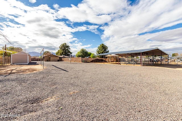 view of yard with an outdoor structure, a shed, and fence