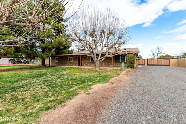 single story home featuring stone siding, fence, a front lawn, and a gate